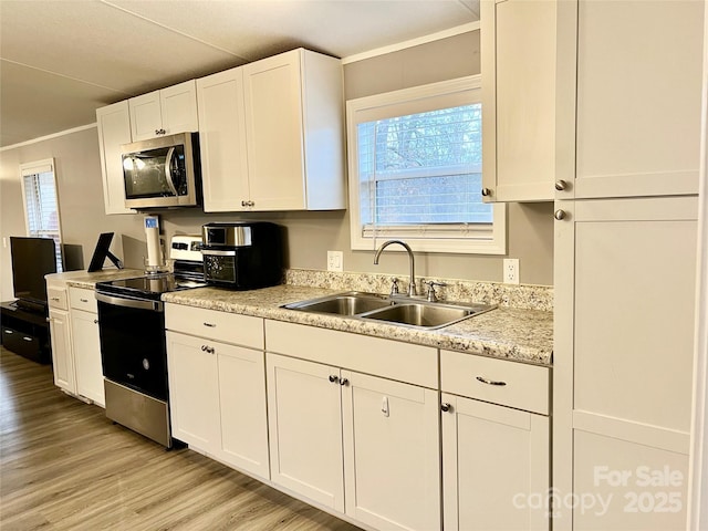 kitchen featuring appliances with stainless steel finishes, white cabinets, crown molding, light hardwood / wood-style flooring, and sink