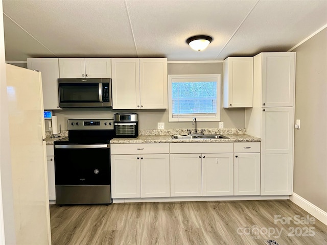 kitchen with a textured ceiling, white cabinets, stainless steel appliances, sink, and light wood-type flooring