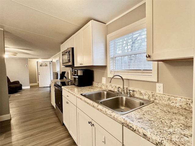 kitchen featuring white cabinetry, appliances with stainless steel finishes, dark hardwood / wood-style flooring, light stone countertops, and sink