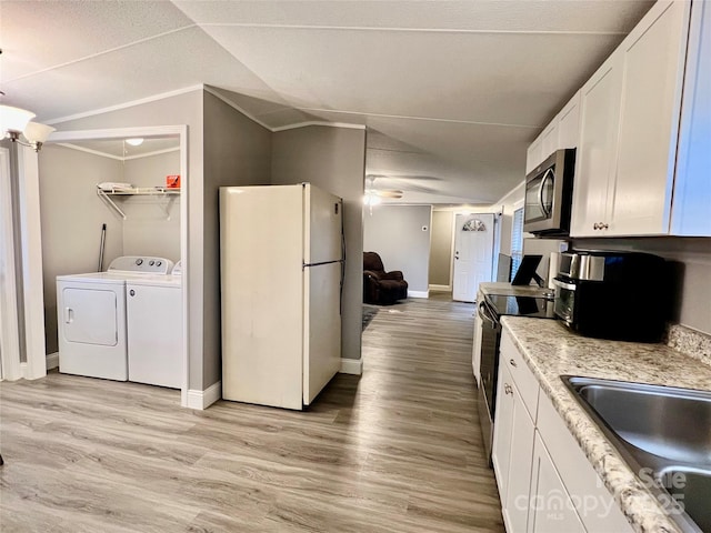 kitchen featuring white fridge, washer and dryer, lofted ceiling, and white cabinets