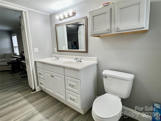 bathroom with toilet, vanity, crown molding, hardwood / wood-style flooring, and a textured ceiling