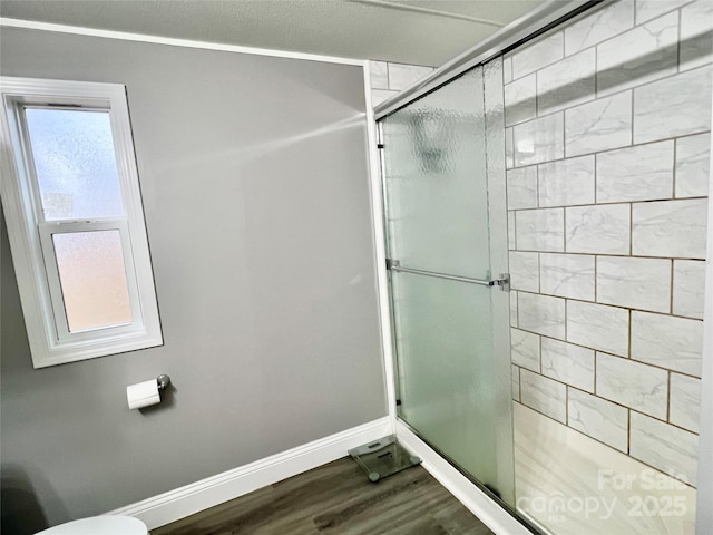 bathroom featuring a shower with door, a wealth of natural light, and hardwood / wood-style flooring