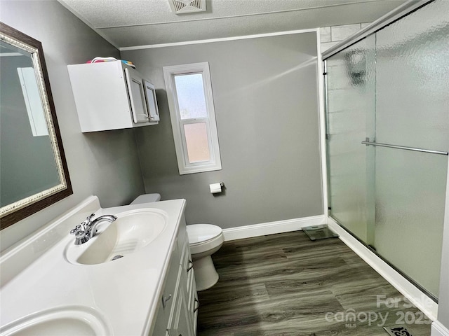 bathroom with toilet, a textured ceiling, a shower with door, and vanity