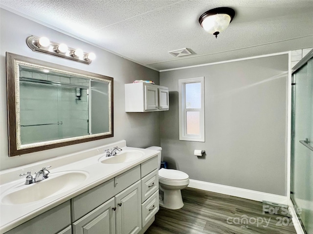 bathroom featuring a textured ceiling, vanity, hardwood / wood-style flooring, toilet, and a shower with shower door