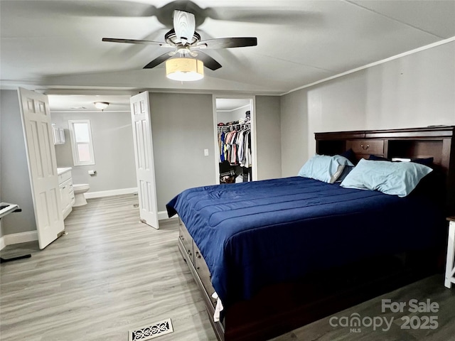 bedroom featuring light wood-type flooring, ceiling fan, ensuite bathroom, and a closet