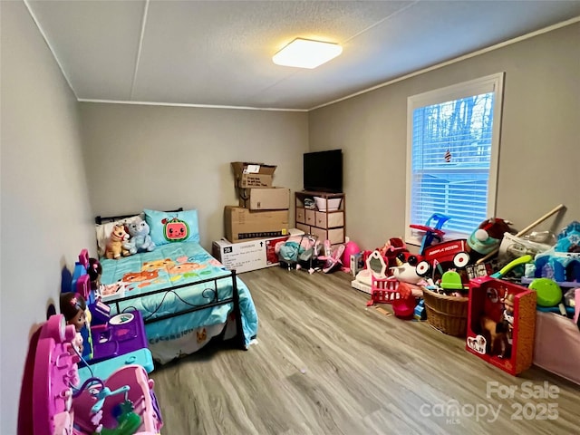 bedroom with a textured ceiling, ornamental molding, and wood-type flooring