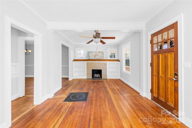 unfurnished living room featuring a tiled fireplace, ceiling fan with notable chandelier, and hardwood / wood-style flooring