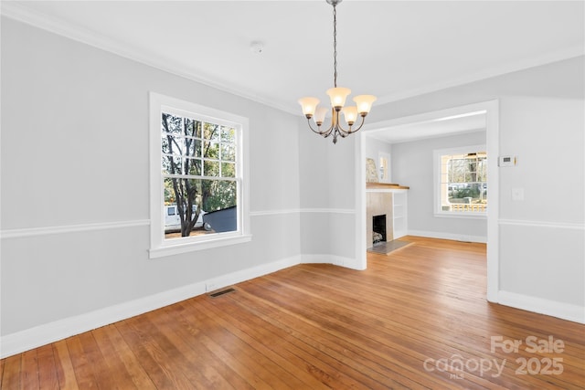 unfurnished dining area with a high end fireplace, hardwood / wood-style floors, and a notable chandelier