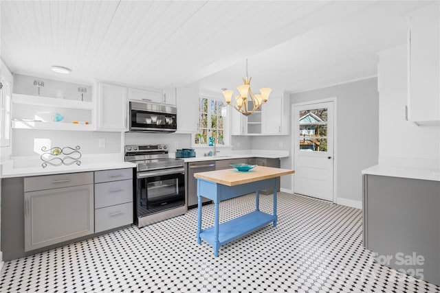 kitchen with hanging light fixtures, appliances with stainless steel finishes, gray cabinetry, and a healthy amount of sunlight