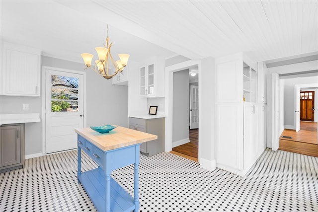 kitchen with hanging light fixtures, white cabinets, butcher block counters, and a kitchen island