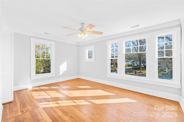 unfurnished room featuring ceiling fan, light hardwood / wood-style flooring, ornamental molding, and a healthy amount of sunlight