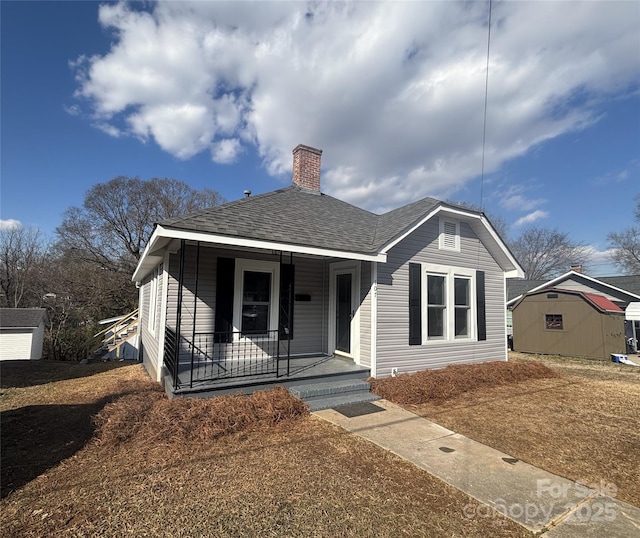 bungalow featuring a porch and a storage shed