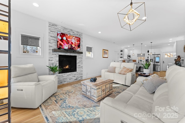 living room with light wood-type flooring, a chandelier, and a fireplace