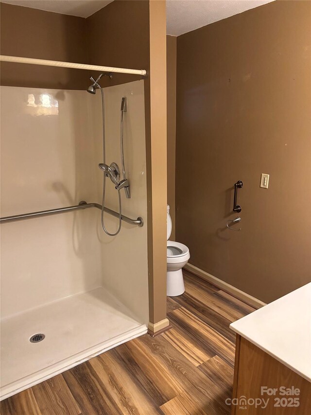 bathroom featuring a shower, wood-type flooring, and toilet