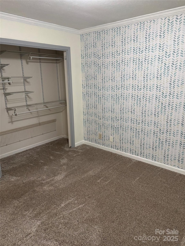 unfurnished bedroom featuring a textured ceiling, a closet, ornamental molding, and carpet flooring