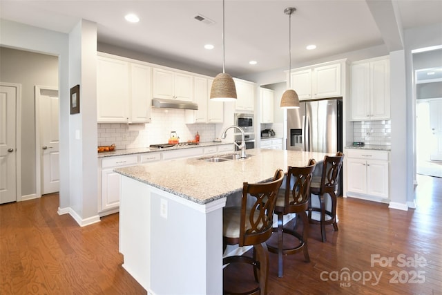 kitchen with sink, stainless steel appliances, light stone countertops, a kitchen island with sink, and white cabinets