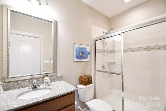 bathroom featuring vanity, toilet, and a shower with door