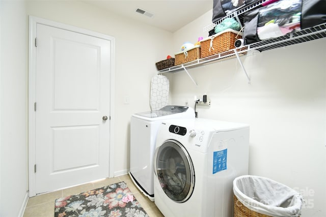 laundry room with washer and dryer and light tile patterned floors