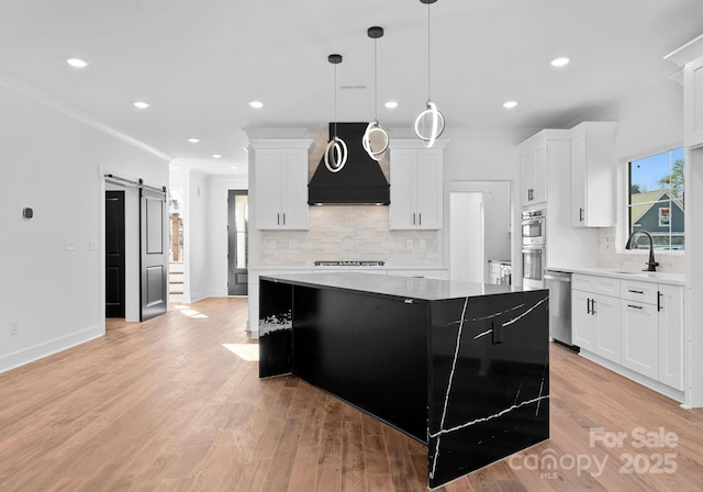 kitchen featuring premium range hood, white cabinetry, a center island, and a barn door