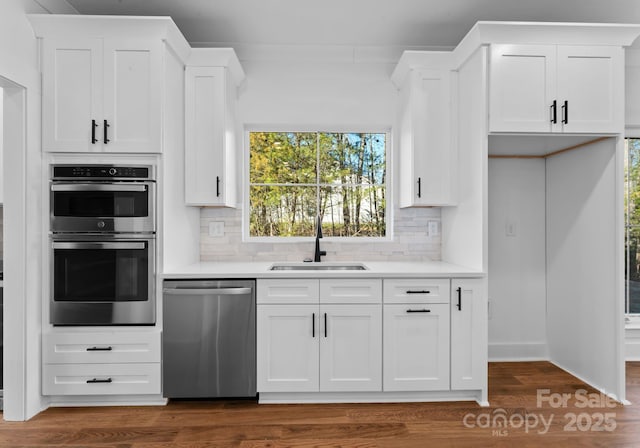 kitchen with backsplash, appliances with stainless steel finishes, sink, and white cabinetry