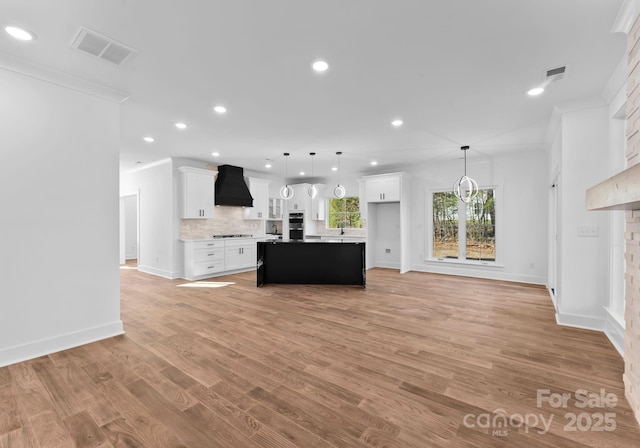 kitchen featuring decorative light fixtures, tasteful backsplash, a center island, custom range hood, and white cabinets