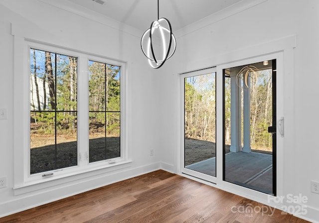 unfurnished dining area featuring plenty of natural light, crown molding, and hardwood / wood-style flooring