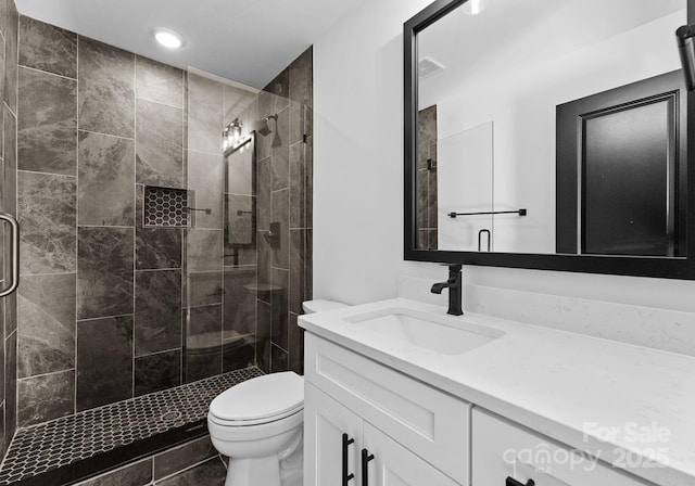 bathroom with a shower with shower door, toilet, and vanity