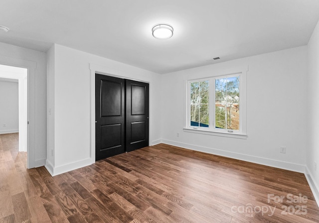 unfurnished bedroom with a closet and hardwood / wood-style flooring