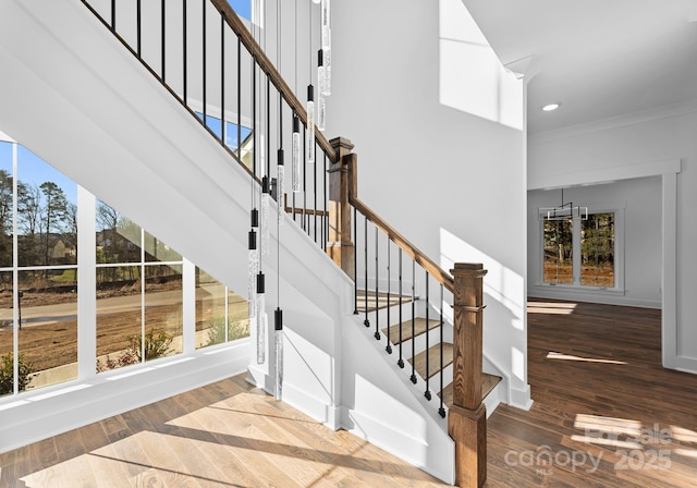 stairway with ornamental molding and wood-type flooring