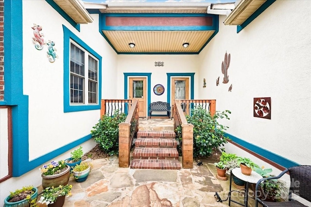 doorway to property with covered porch and stucco siding