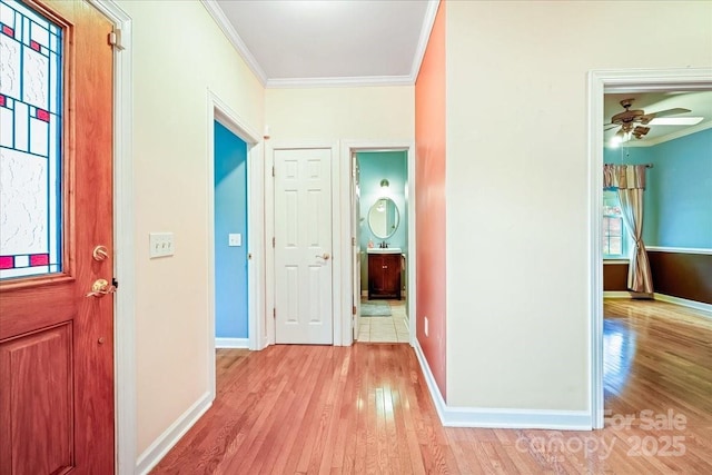 hall featuring light wood finished floors, baseboards, and ornamental molding
