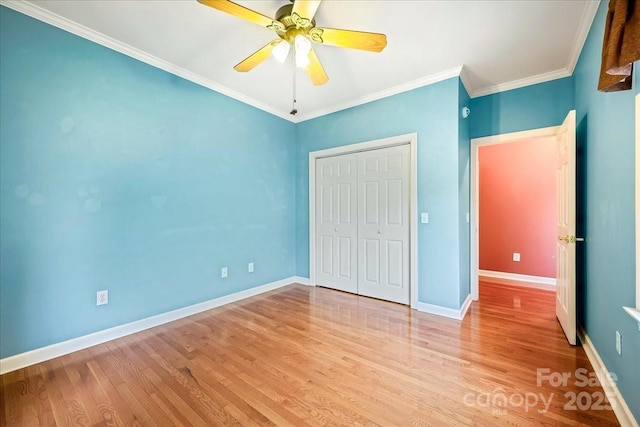 unfurnished bedroom with a ceiling fan, wood finished floors, a closet, baseboards, and ornamental molding
