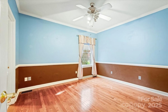 empty room with ornamental molding, baseboards, a ceiling fan, and wood finished floors