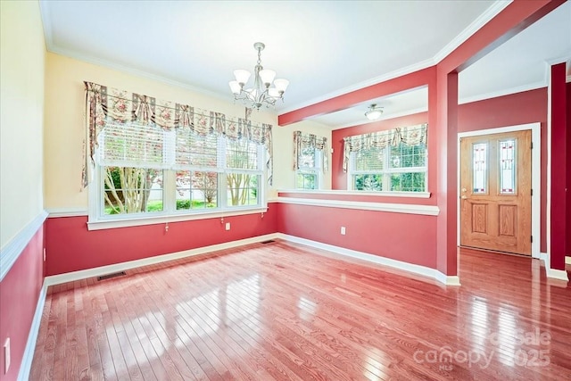 unfurnished dining area with a wealth of natural light, hardwood / wood-style flooring, visible vents, and an inviting chandelier