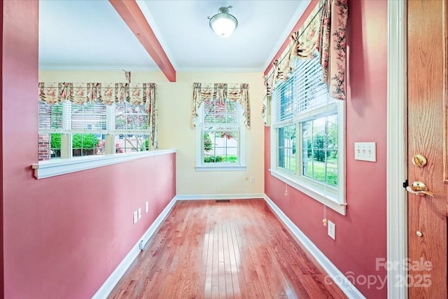 interior space featuring baseboards, visible vents, beamed ceiling, wood finished floors, and crown molding