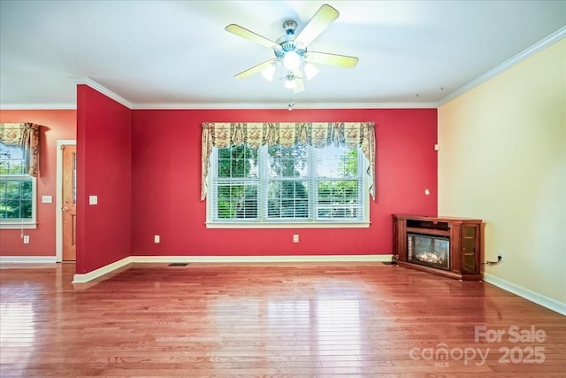 unfurnished living room with a wealth of natural light, a glass covered fireplace, and wood finished floors