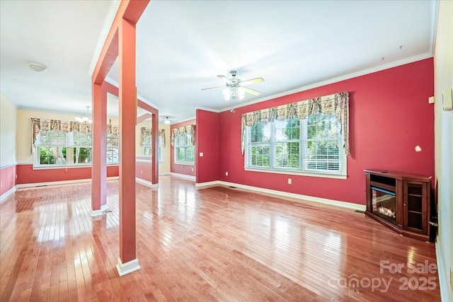 unfurnished living room with light wood-style flooring, a healthy amount of sunlight, baseboards, and decorative columns