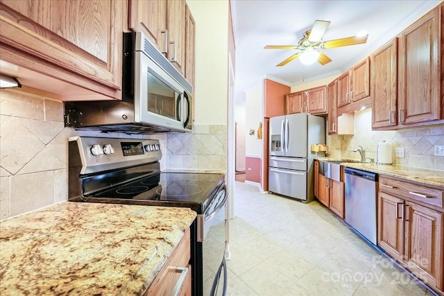 kitchen featuring stainless steel appliances, a sink, tasteful backsplash, light stone counters, and crown molding