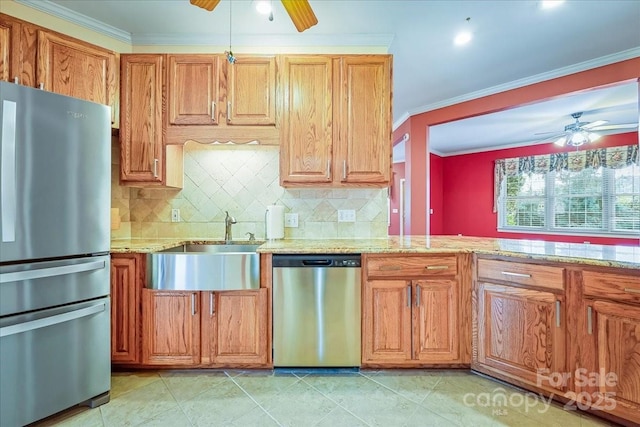 kitchen with light stone counters, appliances with stainless steel finishes, a ceiling fan, and a sink