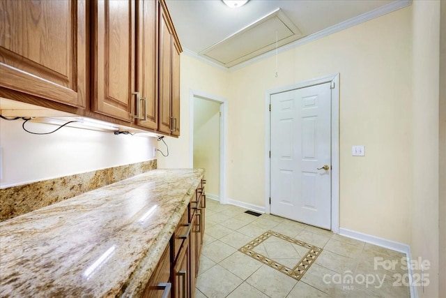 unfurnished dining area with attic access, crown molding, baseboards, and light tile patterned flooring