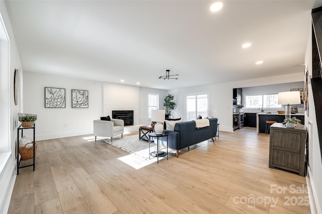 living room featuring a healthy amount of sunlight, a fireplace, and light hardwood / wood-style floors