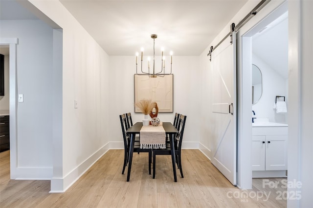 dining area featuring a barn door, light wood-type flooring, and a notable chandelier