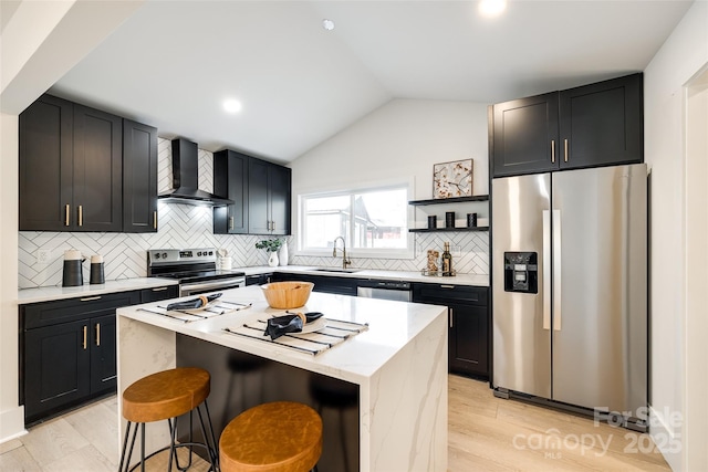 kitchen with appliances with stainless steel finishes, a kitchen island, wall chimney range hood, a kitchen breakfast bar, and vaulted ceiling