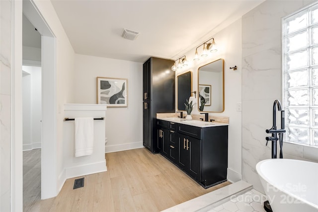 bathroom with a tub, tile walls, hardwood / wood-style flooring, and vanity