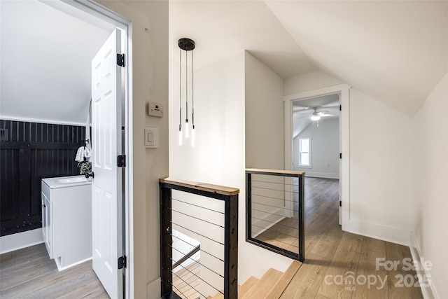 corridor featuring lofted ceiling, light hardwood / wood-style floors, and sink