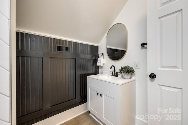 bathroom with hardwood / wood-style flooring, vanity, and lofted ceiling