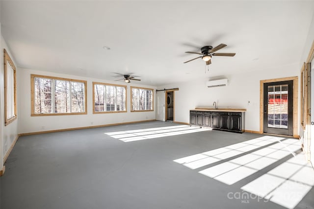 unfurnished living room featuring ceiling fan, a barn door, a wall mounted air conditioner, and concrete flooring