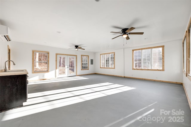 unfurnished living room with a wall unit AC, ceiling fan, french doors, and sink