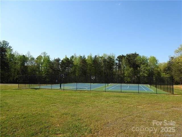 view of tennis court featuring a lawn