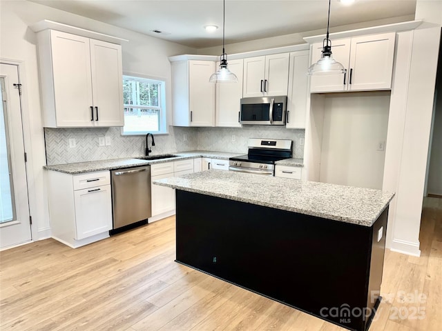 kitchen with sink, appliances with stainless steel finishes, white cabinetry, and decorative light fixtures